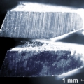 Fot. 2. Zdjęcie mikroskopowe obrazujące różnice w zużyciu między zębem niezmodyfikowanej piły tarczowej (na górze) a zębem piły udoskonalonym w NCBJ za pomocą implantacji jonów (na dole). Ciemniejsze obszary na zębie zmodyfikowanym to odtwarzające się struktury amorficznego węgla. Zdjęcie w kolorach sztucznych. (Źródło: NCBJ/PORTA)